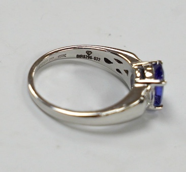 A modern 18ct gold and single stone oval cut tanzanite set ring, with baguette cut diamond cluster set shoulders, with accompanying AnchorCert report, stating the stone to weigh 1.20ct, size L, gross weight 4.1 grams. Co